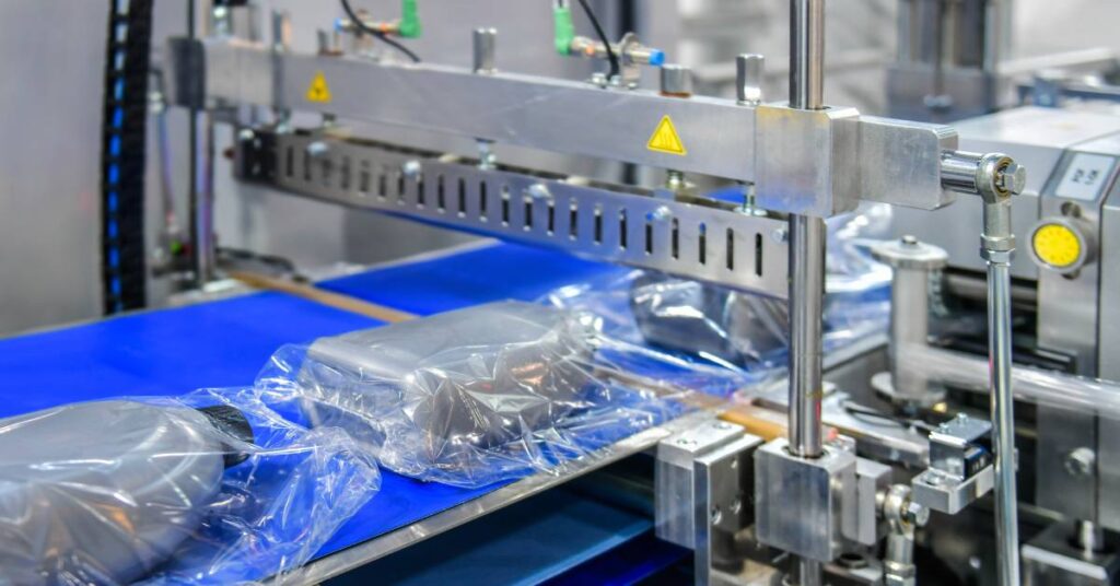 A machine for packaging products on a conveyor belt in a factory, showcasing the process of sealing and preparing products.