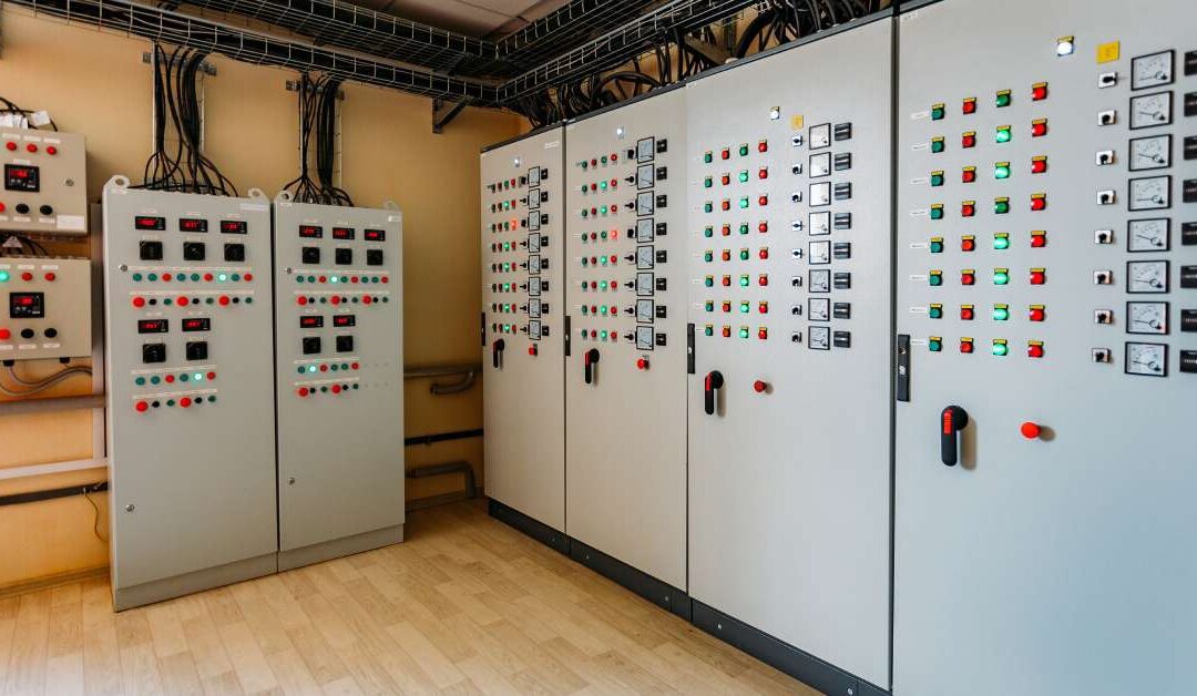 Electrical switchgear cabinet equipped with control panels and lights. The room is clean and well-organized.